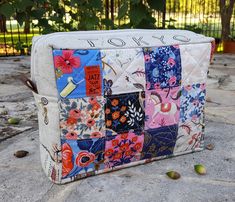 a colorful patchwork cosmetic bag sitting on top of a stone floor next to some nuts