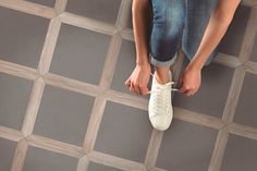 a person sitting on the floor with their feet up and wearing white tennis shoes in front of them