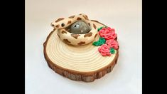 an animal figurine sitting on top of a piece of wood with flowers around it