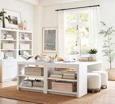 a living room filled with lots of white furniture and bookshelves next to a window