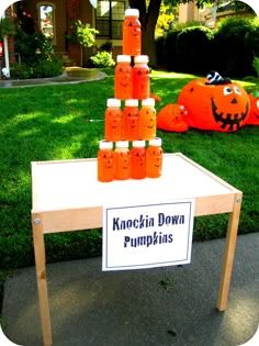 a table with orange juice bottles on it in front of a house and pumpkins