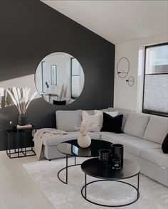 a modern living room with black and white decor on the walls, round mirror above the couch