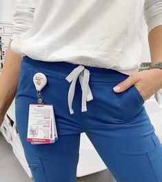 a woman wearing blue pants with a white tag attached to the side of her waist