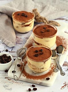 three desserts are sitting on a plate with spoons and chocolate chips around them