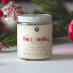 a white candle sitting on top of a table next to christmas ornaments and baubles