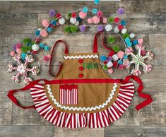 an apron is decorated with pom poms and other holiday decorations on a wooden floor