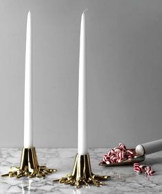 three white candles on a marble table with candy canes