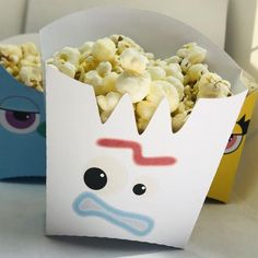 two boxes filled with popcorn sitting on top of a white table next to each other