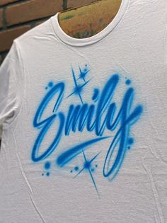 a white t - shirt with blue graffiti on it