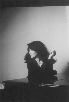 a black and white photo of a woman sitting at a desk with her hair in the air