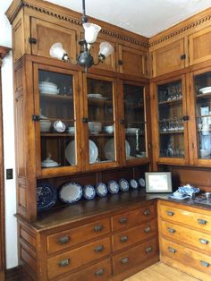 an old fashioned kitchen with wooden cabinets and dishes on the counter top, along with other antique china