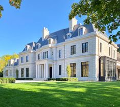 a large white house with lots of windows on it's sides and grass in the front yard