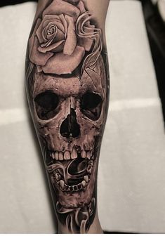 a man's leg with a skull and rose tattoo design on the calf sleeve