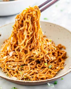 the noodles are being lifted with chopsticks in a bowl, ready to be eaten