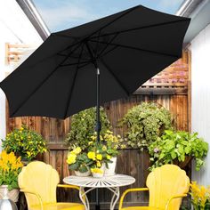 two yellow chairs and an umbrella are on the back patio with potted planters