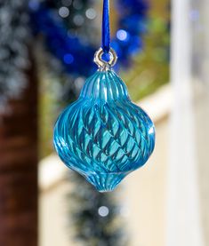 a blue glass ornament hanging from a tree