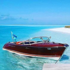 a boat is parked in the water near a dock on an island with white sand and clear blue water