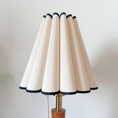 a wooden table lamp with white lampshade and black trimmings on it