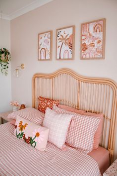 a bed with pink and white checkered sheets, pillows and pictures on the wall