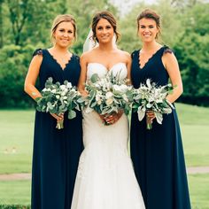 three bridesmaids pose with their bouquets in front of the green grass and trees