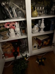 the shelves are filled with various items and flowers in vases, bookshelves, and candles