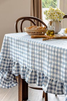 a blue and white checkered table cloth on a wooden chair next to a vase with flowers