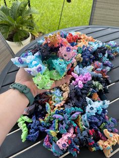 someone is holding their hand out over a pile of fake flowers on a patio table