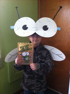 a young boy holding up a book with two faces on it