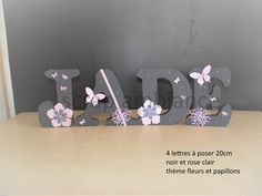 the letters are made out of wood and have pink flowers on them, with butterflies