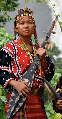 two women in native garb holding an instrument