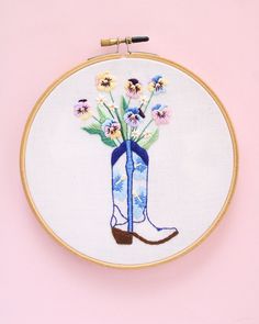 a blue boot with flowers in it on a pink background embroideryed into a hoop