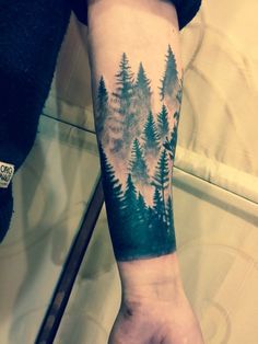 a person with a forest tattoo on their arm