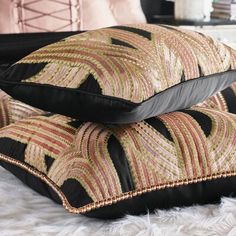 two black and gold pillows sitting on top of a white furnishing covered floor