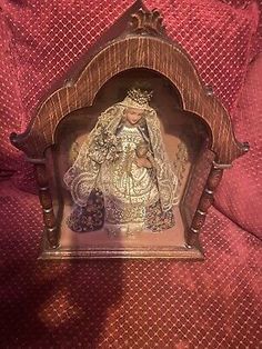 an ornate wooden frame with a virgin mary and baby jesus in the center on a red blanket