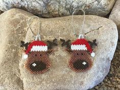 a pair of reindeer earrings with santa's hat on them sitting on top of a rock