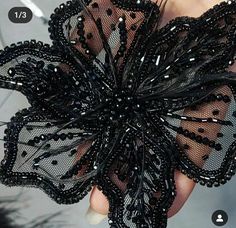 an image of a woman's hand holding a black lace flower