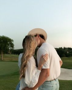 a man and woman kissing in front of a golf course