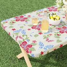 a bowl of fruit sitting on top of a table covered in a flowered cloth