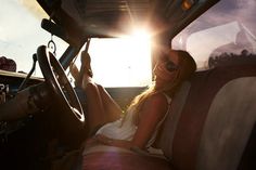 a woman sitting in the driver's seat of a truck with sun shining through