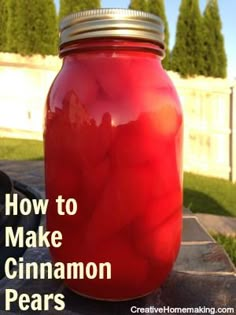 a mason jar filled with red liquid sitting on top of a stone slab in front of a white fence