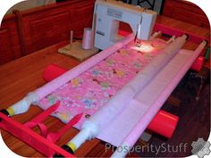 a sewing machine sitting on top of a wooden table next to a pink and white quilt