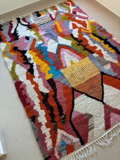 a multicolored rug with fringes on the floor next to a door way