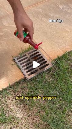 a person is using a grate to drain water into the ground with a red and green sprinkler