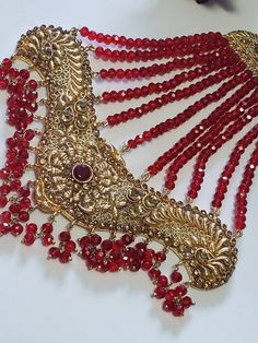 an elaborate necklace with red beads and gold trimmings on it's neck