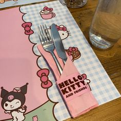 a hello kitty place mat with a fork and knife on it next to a glass of water