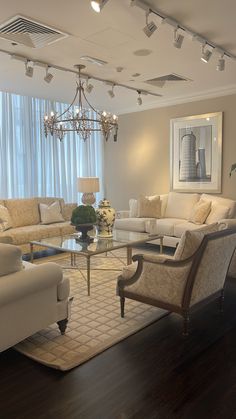 a living room filled with furniture and a chandelier hanging over the top of it