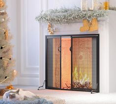 a cat laying on the floor in front of a fire place next to a christmas tree