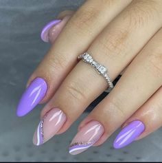 a woman's hand with purple and white nail polish on her nails, holding a diamond ring