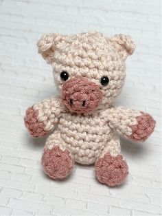 a small crocheted teddy bear sitting on top of a white brick wall with eyes wide open