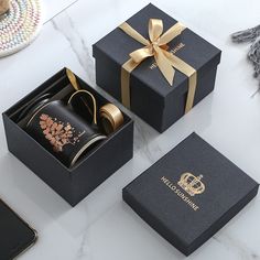 three black boxes with gold ribbon and decorative designs on them, one is open to show the contents